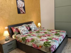 a bedroom with a bed with a floral comforter and two lamps at Sun House in Montesilvano