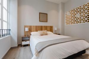 a bedroom with a large white bed with a wooden headboard at Casa Love by Wynwood House in Panama City