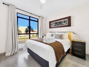 a bedroom with a large bed and a large window at Renovated, Pools, Park, Gym, Parking, Canal walk access in Cape Town +32 photos
