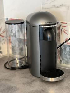 Una cafetera colocada sobre un mostrador junto a un vaso. en W&L Paris Apartment 68m - 3 min Métro 4 - A Paris Centre 15min, en Bagneux