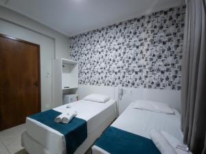 deux lits dans une petite pièce avec un mur dans l'établissement Hotel San Telmo, à Aparecida