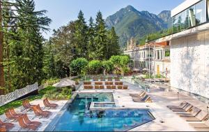 a resort with a swimming pool and mountains in the background at HONEY Moonspa in San Pellegrino Terme