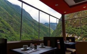 a restaurant with two tables and a view of mountains at Hotel Ferré Boulevard in Machu Picchu