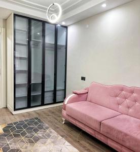 Sofá rosa en la sala de estar con puertas de cristal en Midyat Merkezde Lüks Daire en Midyat