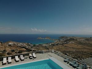 a swimming pool with chairs and a view of the ocean at Mykonos Supreme Comfort Suites & Villas in Kalafatis