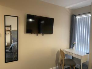 a room with a table and a television on the wall at Roskeen Townhouse in Belfast