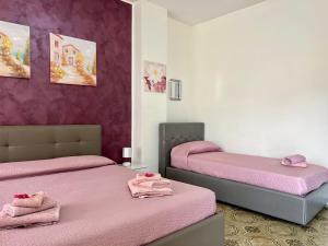due letti in una stanza con lenzuola rosa di Appartamento Donna Carmela a Tropea