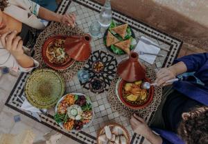 un grupo de personas sentadas en una mesa con comida en Riad Bab Ahmar en Marrakech