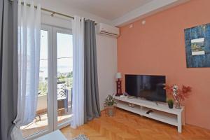 a living room with a tv and a large window at Apartment & Rooms Meri Tučepi in Tučepi