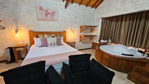 a bedroom with a tub and a bed and chairs at Chalé Gosto da Roça in Monte Verde