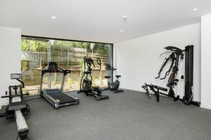 a gym with several tread machines and a large window at Beach Getaway in Mount Maunganui