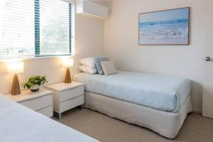 a bedroom with a bed and two lamps and a window at Charming Riverside Noosa gem in Noosaville