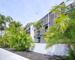 a white building with palm trees in front of it at Beach Getaway in Mount Maunganui