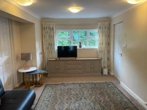 a living room with a tv and a couch and a window at Brambles, Ebford, Devon in Exeter