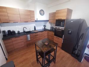 a kitchen with a black refrigerator and a table at Bel Appartement pour 1 à 9 personnes in Ambert +9 photos