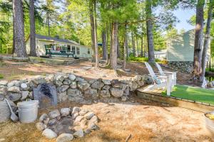 a backyard with a stone wall and a fire pit at Pet-Friendly Waterfront Cottage On-Site Bunkhouse in East Wakefield
