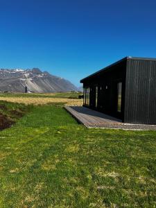 a black building in a field with mountains in the background at REY Stays - House in Höfn