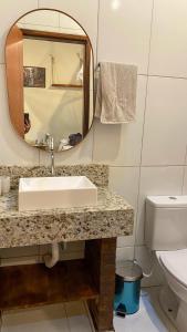 a bathroom with a sink and a mirror and a toilet at Chalé Mascarenhas in Ibicoara
