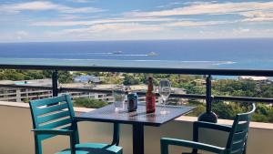 een tafel met 2 stoelen, flessen en glazen op een balkon bij Kaili Ocean view luxury 2BR AC throughout Fiber Wifi & Pool in Papeete