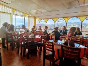 a group of people sitting at tables in a restaurant at Pukantu Hostal in Puno