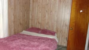 - une chambre avec un lit rose et un mur en bois dans l'établissement NiceShortStayMassena, à Massena