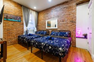 1 Schlafzimmer mit 3 Betten und Ziegelwand in der Unterkunft Studios in New York in New York