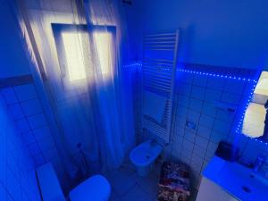 La salle de bains est pourvue de toilettes et d'un lavabo avec des lumières bleues. dans l'établissement Incredibile Appartamento con doccia Idromassaggio, 