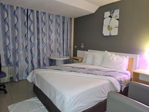 een hotelkamer met een groot bed met witte lakens bij Golden Tree Hotel Belize in Belize City