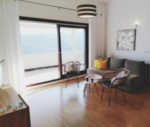 een woonkamer met een bank en stoelen en een groot raam bij Sea View K Loft in Rabac +10 foto's