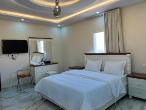 Schlafzimmer mit einem Bett, einem Schreibtisch und einem TV in der Unterkunft شقق سطام المخدومة in Al Fayşalīyah
