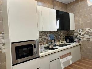 a small kitchen with white cabinets and a microwave at شقق سطام المخدومة in Al Fayşalīyah