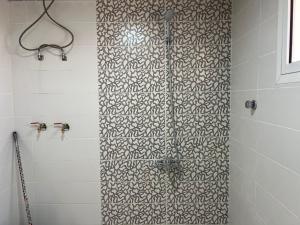 eine Dusche mit schwarz-weißem Muster in der Unterkunft شقق سطام المخدومة in Al Fayşalīyah