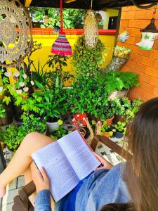 a woman reading a book in front of plants at Maga hospedagem in Penha