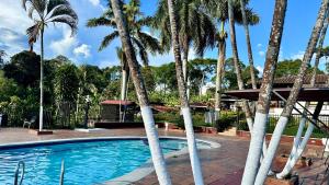 a pool with palm trees in front of a house at HOTEL CAMPESTRE CARRIEL QUINDIO picnic in Montenegro