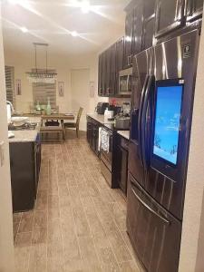 eine Küche mit einem Kühlschrank und einem TV in der Unterkunft Troy@Kissimme in Kissimmee