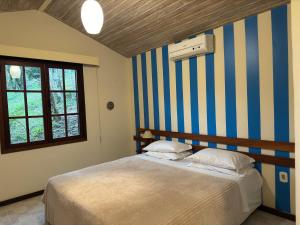 a bedroom with a bed with a striped wall at Pousada Peninsula de Buzios in Búzios