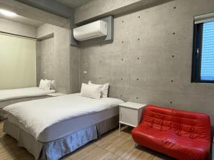 a bedroom with two beds and a red chair at Mei Jen House B&B 民宿 in Yuchi