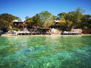 a group of houses on a beach with the water at El Hamaquero Hostal EcoNativo in Isla Grande