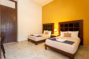a bedroom with two beds and a yellow wall at Tecnohotel Casa Villamar in Progreso +43 photos