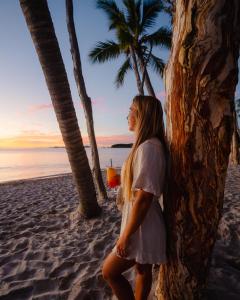 una mujer de pie en la playa con una bebida en Great Keppel Island Hideaway, en Isla Great Keppel