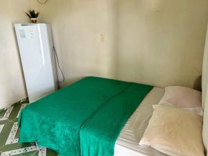 a green blanket on a bed in a room with a refrigerator at Vila alegria in Salinópolis