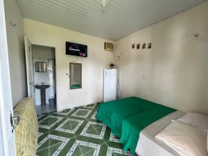 a room with a refrigerator and a green blanket on the floor at Vila alegria in Salinópolis