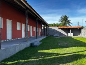 a red building with a grass yard next to a building at Vila alegria in Salinópolis