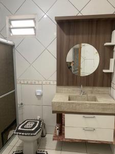 a bathroom with a sink and a toilet and a mirror at AP próximo ao aeroporto, praia, porto e Beto carrero in Navegantes