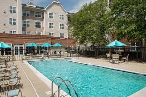 uma piscina com cadeiras e guarda-sóis azuis em Residence Inn Silver Spring em Silver Spring