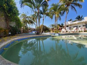 a swimming pool with palm trees and a house at LA PUCCA HOTEL BOUTIQUE RESORT in La Peñita de Jaltemba