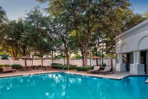 uma piscina com cadeiras, mesas e árvores em Sheraton Suites Market Center Dallas em Dallas
