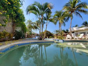 a swimming pool with palm trees and a house at LA PUCCA HOTEL BOUTIQUE RESORT in La Peñita de Jaltemba