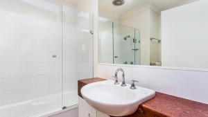 a white bathroom with a sink and a shower at Sunrise Cove Holiday Apartments by Kingscliff Accommodation in Kingscliff