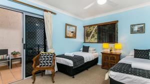 a bedroom with two beds and a window and a chair at Sunrise Cove Holiday Apartments by Kingscliff Accommodation in Kingscliff